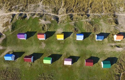 Les cabines de Gouville. Ces petits cabanons en bois colores ont une histoire. Il y a environ un siecle, a l'arrivee des touristes et de la mode des bains de mer, le seul hotel de l'epoque proposait a ses clients de se rendre a la plage en carriole tiree par un cheval et de se changer dans une petite cabane afin de pouvoir apprecier les bienfaits vivifiants de la mer. Gouville-Sur-Mer, FRANCE-26/02/2016