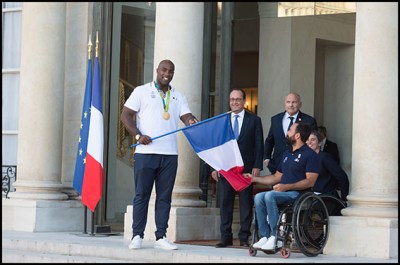 French gold medal winner and judoka Teddy Riner (L) flanked by French President Francois Hollande (2nd L) gives a French national flag to France's flag bearer .Michael Jeremiasz for the Rio Paralympic Games Members of the French Olympic team at the Elysee Presidential Palace for a greeting ceremony with French President Francois Hollande. Paris, FRANCE-23/09/2016